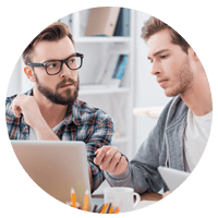 Two young professional men working at laptop.