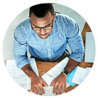 Business man working on laptop computer with papers around him