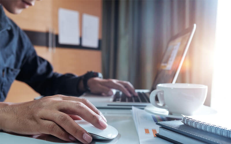 Close up of man's hands on mouse and laptop keyboard device