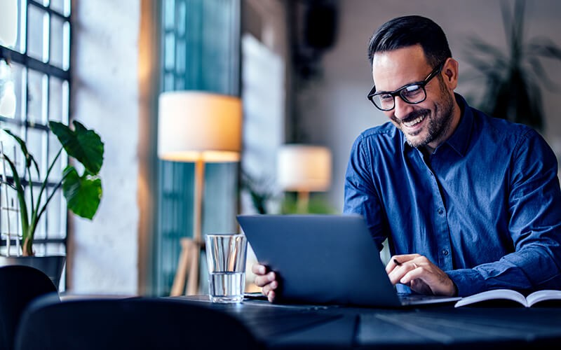 Smiling businessman on laptop computer in open office