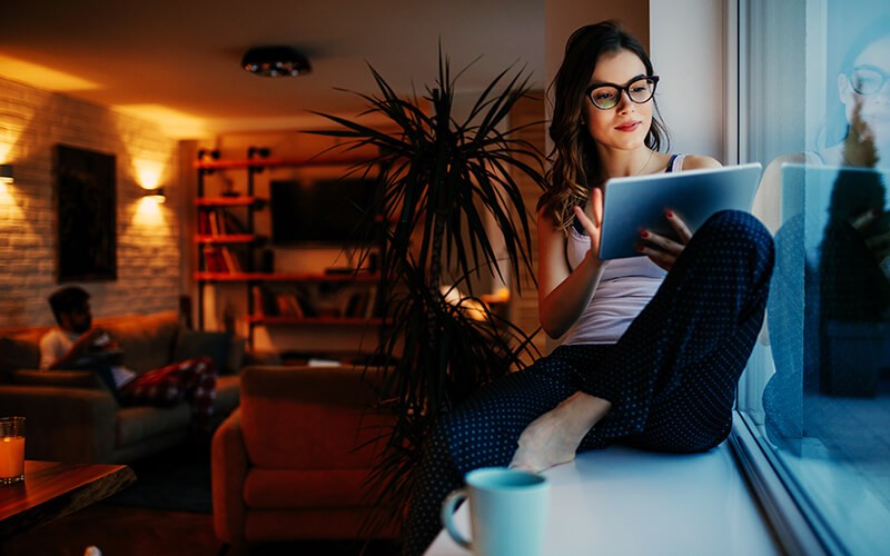 Creative woman working by a window on her tablet.