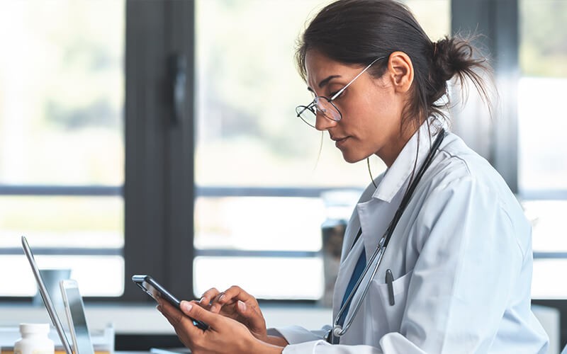 Doctor using a laptop and a android phone