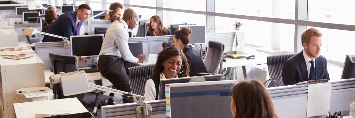 Busy office with employees working at desk on desktops.