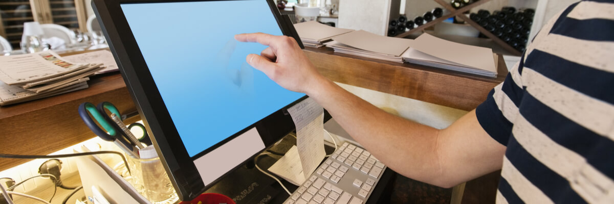 Cropped image of cashier touching computer screen at restaurant counter