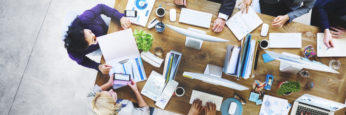 A group of business people collaborate across multiple devices at a meeting. 