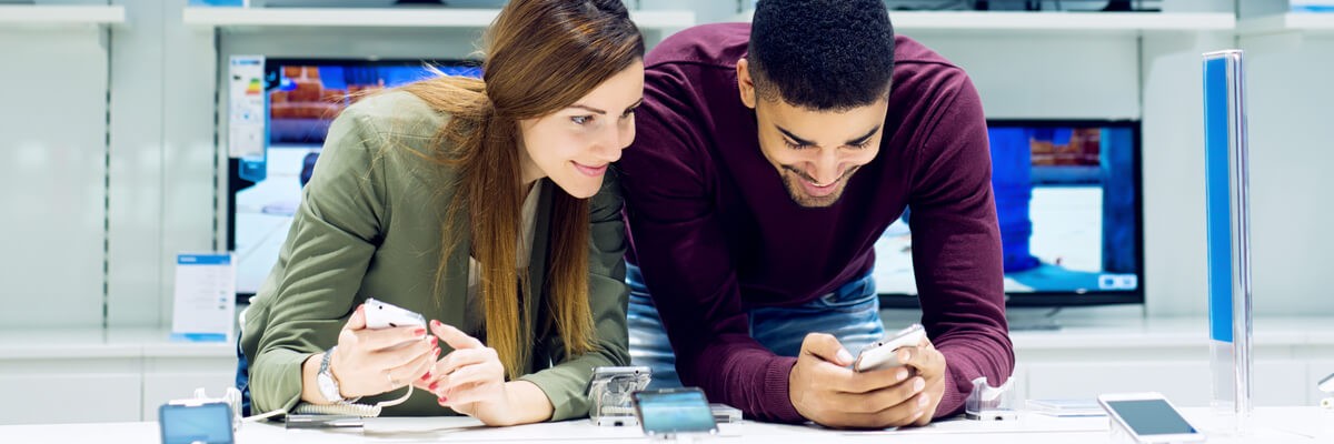 A couple looking at smartphones in an appliance store