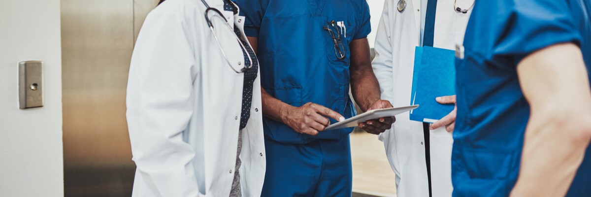 Doctors review patient data off tablet computer in hallway of hospital