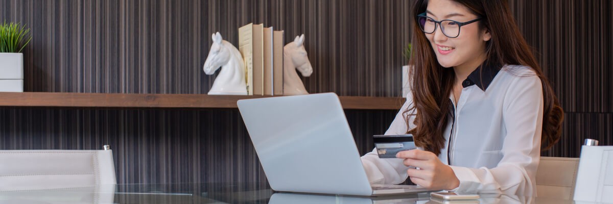 A woman is shopping on a laptop and smiling.