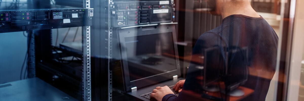 Young it engineer business man with thin modern aluminum laptop in network server room