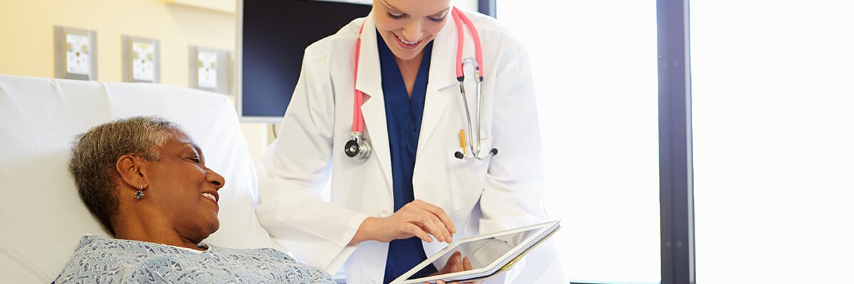 Doctor interacts with patient while using a tablet.