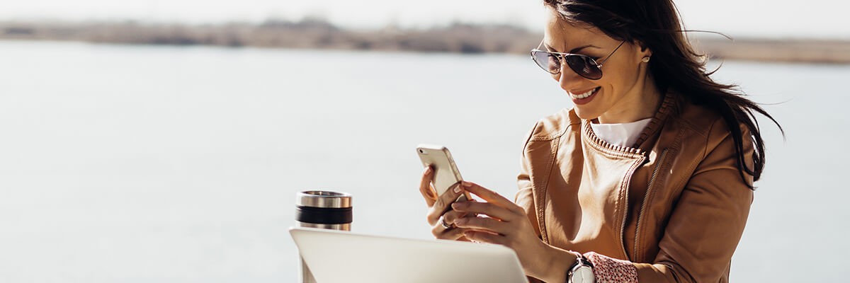 Young businesswoman checking emails on her phone outdoors