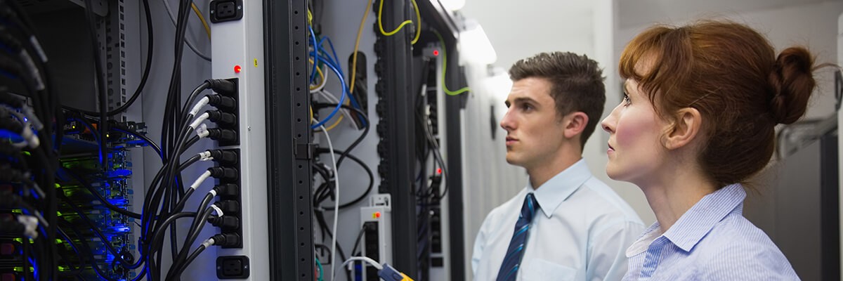 Team of technicians using digital cables on servers in large data center.