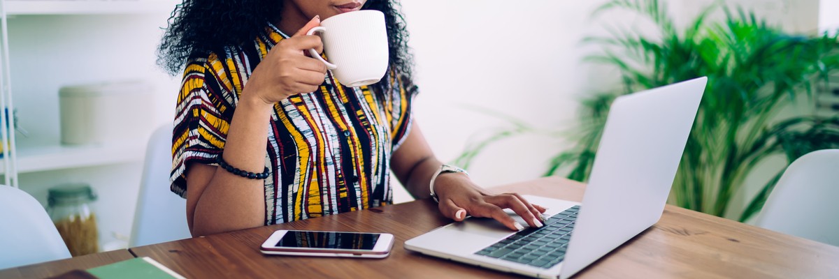 Woman working on a laptop while drinking coffee 