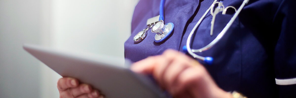 Female doctor typing on digital tablet computer in hospital or surgery. Patient experience