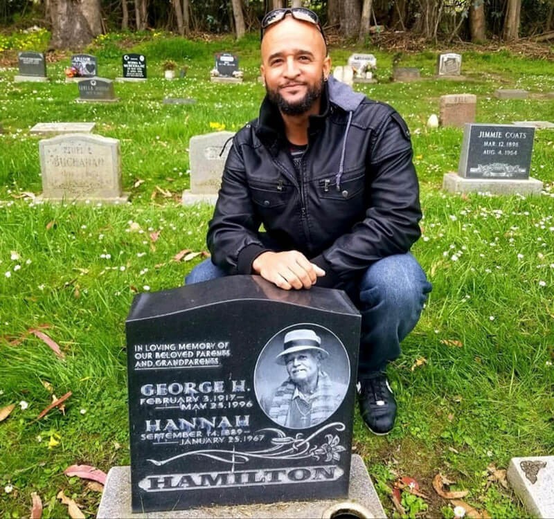 Royce Hamilton posing in front of his grand fathers memorial