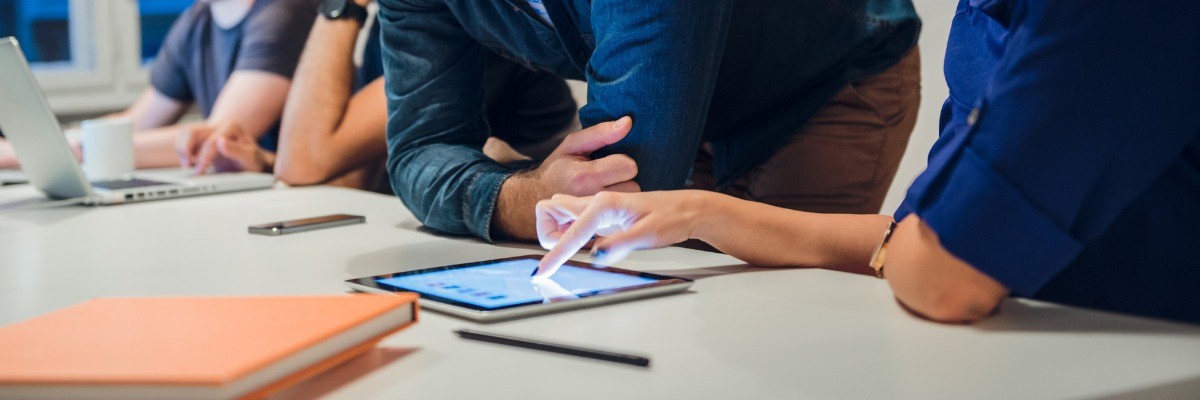 Man and woman are looking at a tablet on a table.