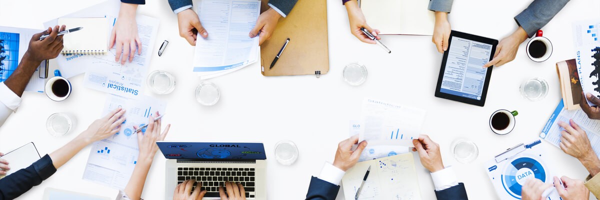 Photo of bird's eye view of a conference table with business professionals gathered around