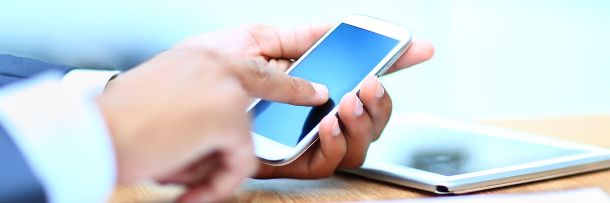 Federal employee sitting at table with smart phone and tablet in hand