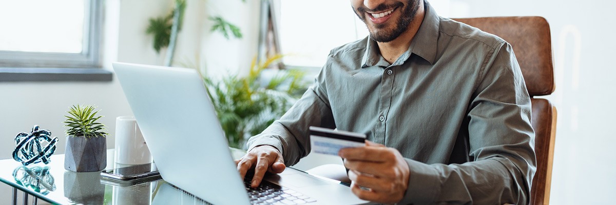 Male user using laptop and holding credit card