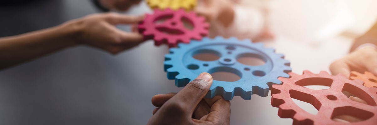 Close up of hands with gear like puzzle pieces symbolizing teamwork