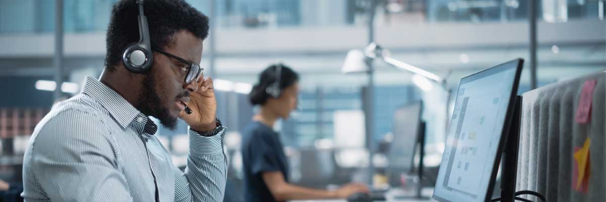 Businessman with headset using computer with Adobe Creative Cloud and Microsoft Teams