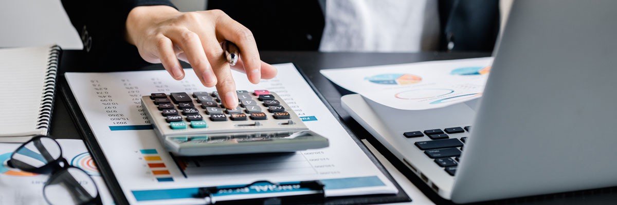 Close up of financial analyst using calculator and laptop device