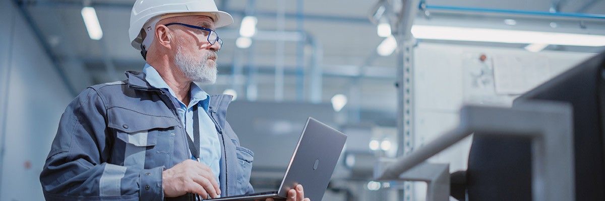 Man in manufacturer warehouse working on laptop