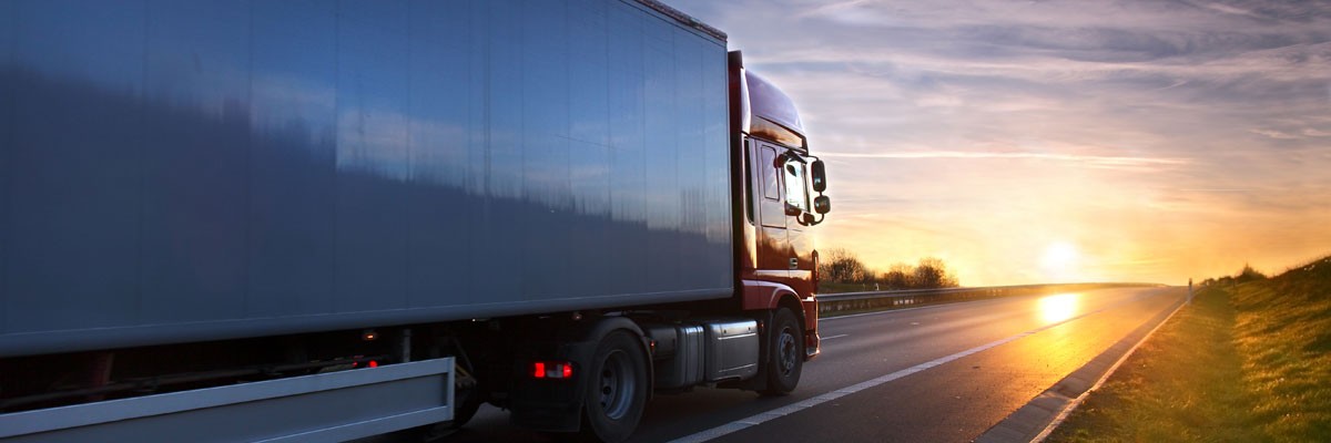 Semi-truck driving on highway at sunset