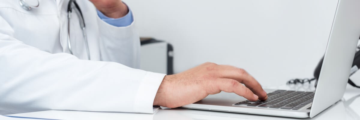 Doctor using laptop with hang on chin