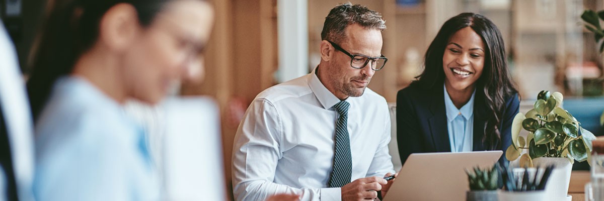 Two business professionals look over managed service options on laptop device