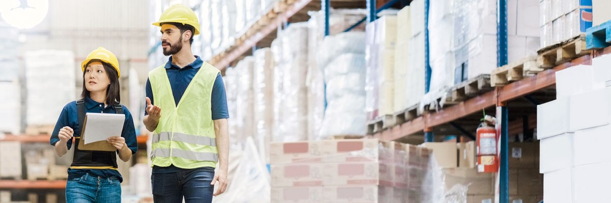 Two employees with hardhats walk through shipping warehouse