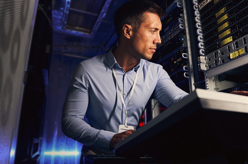 IT engineer reviewing cybersecurity on tablet device in server room