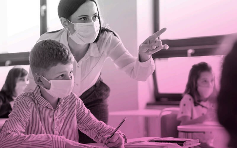 Teacher helping student at classroom desk