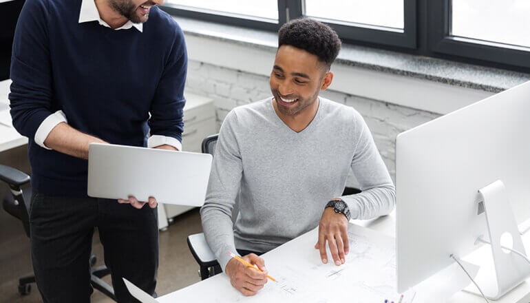 Two business men talking and pointing to laptop screen