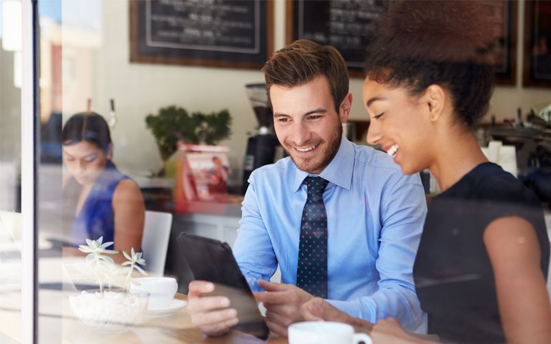 Business professionals with tablet meet in cafe