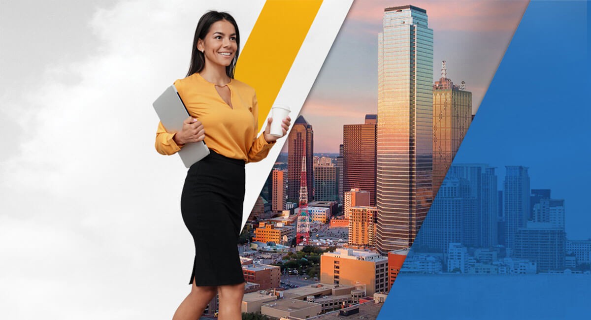 Woman carrying a coffee in one hand and a computer laptop in the other smiles while walking in front of city landscape