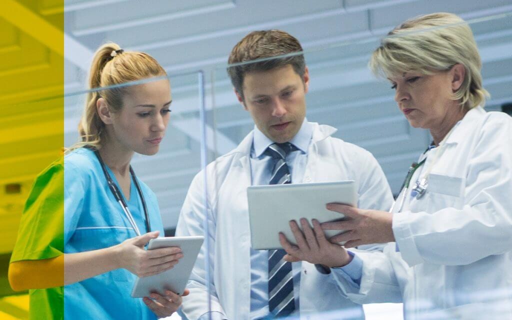 Doctor with nurses reviewing patient data on tablet computers