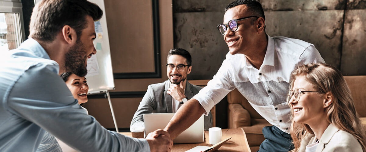 Business people shaking hands over desk in a positive demeanor