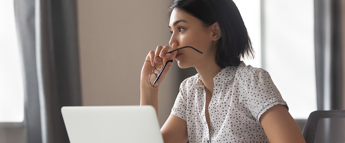 Woman with laptop holding eye glasses