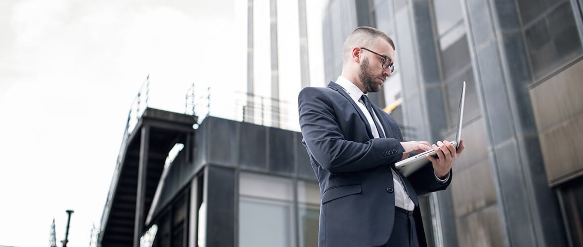 Businessman outside building working on laptop