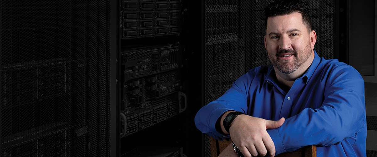 Dan Groves, VP of IT for Westerra Credit Union sits in front of a server rack. 