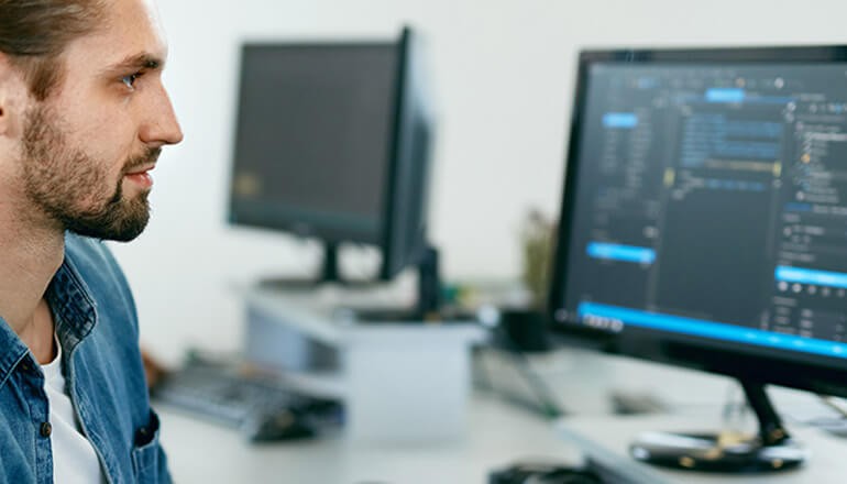 man writing code on desktop computer