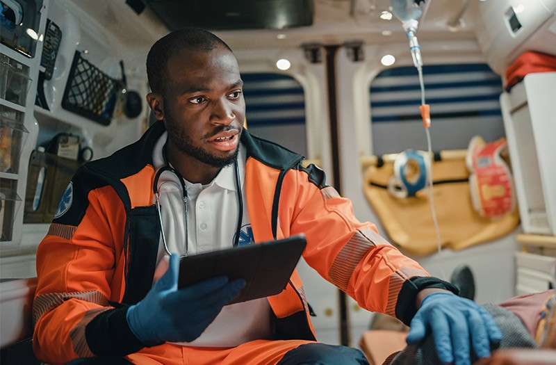 Paramedic using technology device in ambulance