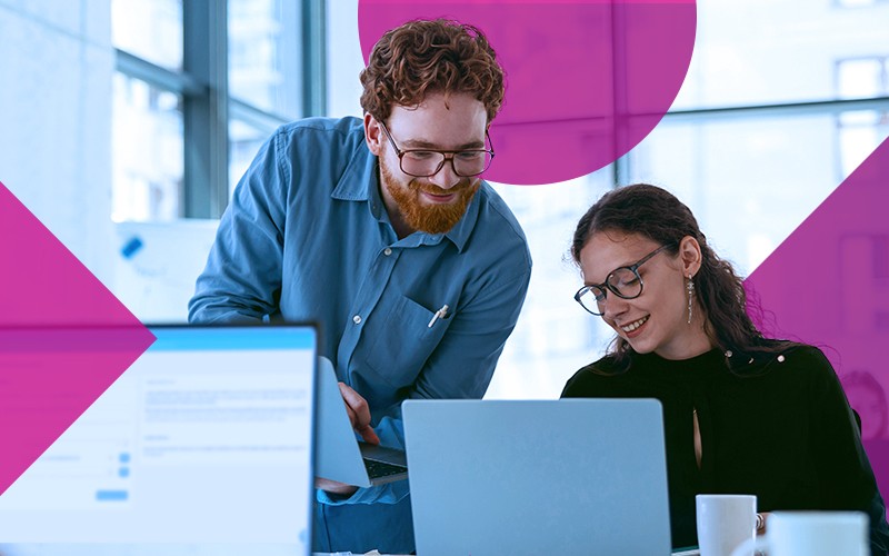 two workers looking at a laptop at work