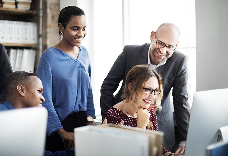 Business men and women gathered around a computer