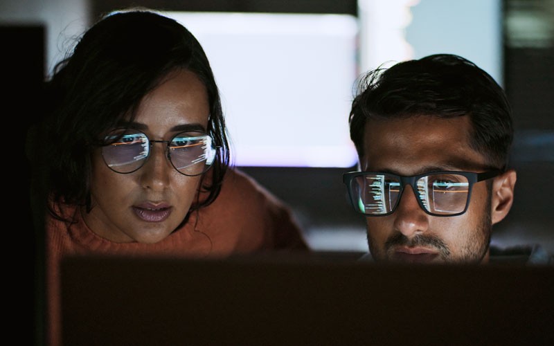 Two IT security engineers using Cisco Umbrella on desktop computer