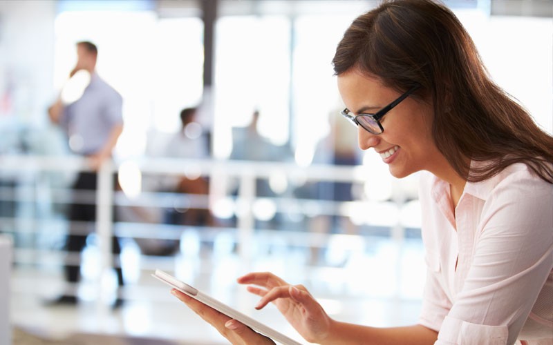 Business woman smiling while using tablet device