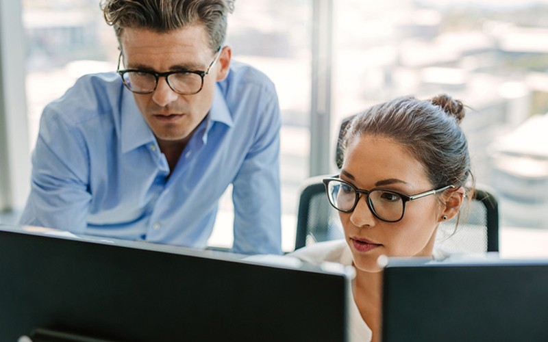 Two coworkers looking over desktop screen