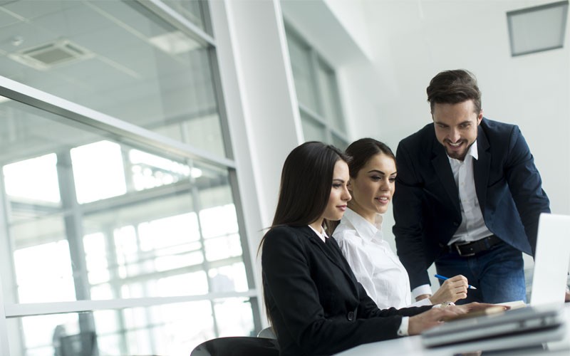 Team of three collaborating over laptop device