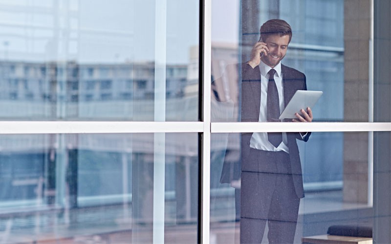 Business man on mobile phone while holding tablet device